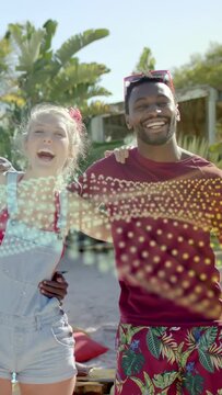 Vertical video: On playing, couple leaning and singing poolside, wave crossing faces for travel ad