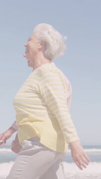 Vertical video: Senior couple walking beach for health, woman stepping ahead causing color bars