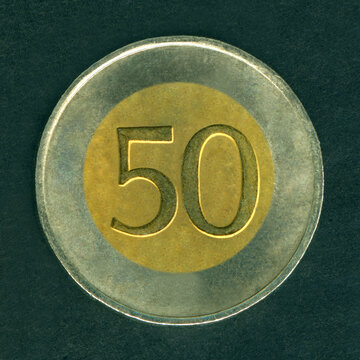 Round bimetallic (brass center, copper-nickel rim) token with a denomination of 50. Isolated on black.