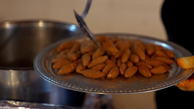 Close-up of freshly cooked kibbeh being removed from hot water and placed on a tray, showcasing traditional Middle Eastern cuisine, final cooking stage, and ready-to-serve food preparation.