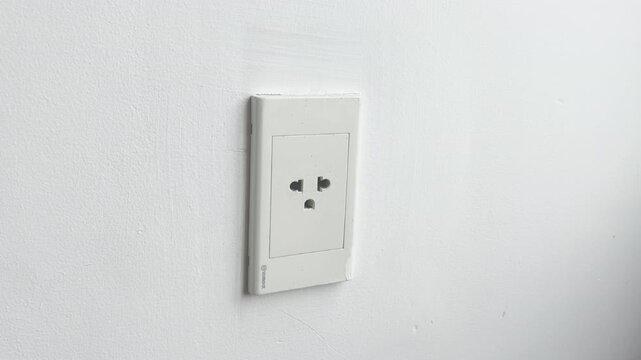 Close-up video of a hand unplugging an electrical plug from a wall socket