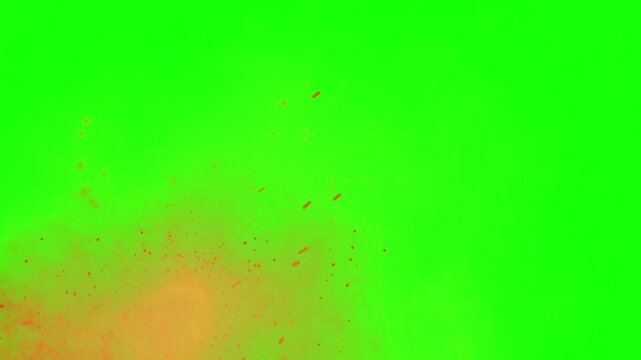 Abstract orange and red particles exploding in slow motion against a vibrant green screen background