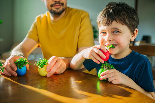 Family smiling and eating fresh microgreen from Easter egg indoors