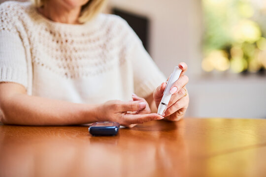 Woman checking blood sugar level with diabetes testing device at home