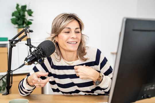 Podcast host recording in a studio with a microphone and computer