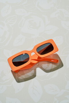 Orange sunglasses minimal style bold plastic frame floral background