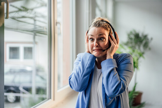Frustrated businesswoman making face talking through headset in office