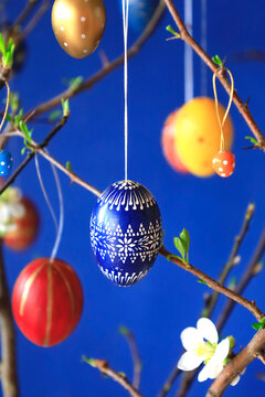 Decorated Easter egg hanging on wild quince branch in spring