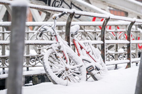 Snow covered red bicycle leaning against a bridge in Hamburg