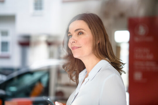 Thoughtful mature businesswoman at office with reflection on window glass