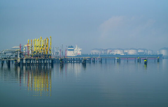 Oil tanker and storage tanks in foggy Rotterdam harbor Netherlands