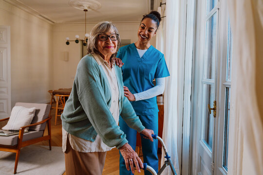 Senior with walker receiving assistance from caregiver at home