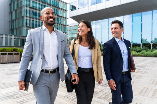 Smiling coworkers walking together outdoors at financial district