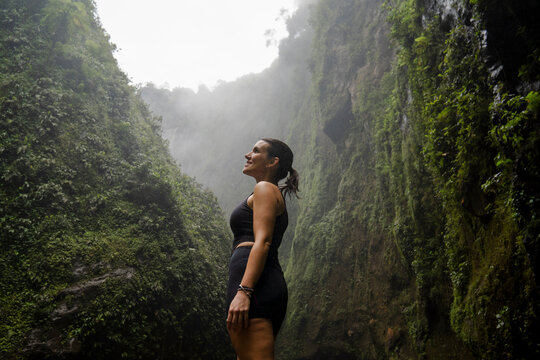 Tourist looking up in lush Tumpak Sewu Waterfall jungle