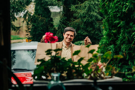 Smiling shopper returning to suburban home with shopping bag