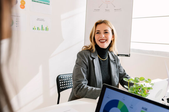 Happy young businesswoman working with colleague in office