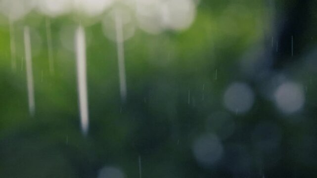Heavy rain falling with a soft, out-of-focus green background and bright bokeh lights