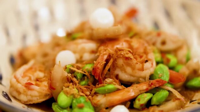 A close up cinematic view of delicious shrimp and green peas stir fry on white plate, dynamic footage.
