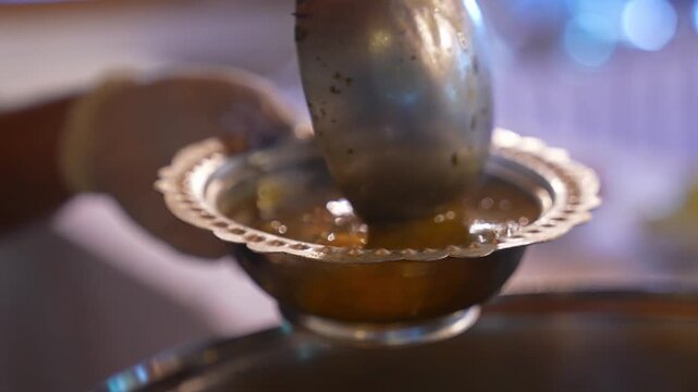 Close-up of hot soup being served into a bowl with a ladle, showing final serving stage, rich texture, and traditional homemade food presentation in a kitchen setting.