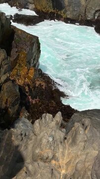 A static vertical view of a rocky outcrop being battered by waves off the coast of Pite, Papudo, Chile