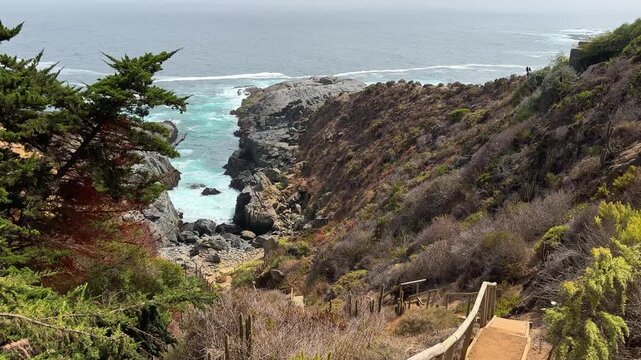 A handheld view of the rustic stairs leading down to the natural breakwater at Punta Pite Beach on Chile&rsquo;s central coast