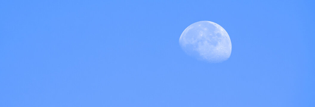 The moon visible in a bright daytime sky, creating a serene celestial contrast and highlighting nature&rsquo;s subtle beauty during daylight hours.