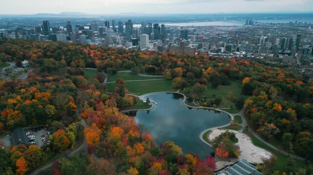 Aerial shot over Mont Royal park in Montreal city during fall season with the lac aux castors in the foreground and the city in the background, Quebec Province, Canada