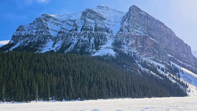 Scenic Banff ski resort view captures rugged Canadian Rockies mountains, evergreen woodland, snowy alpine slopes, and bright winter daylight.