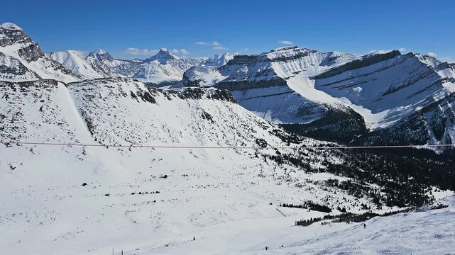 Banff, Canada winter ski scene with people gliding downhill through bright alpine snow and panoramic Canadian Rockies scenery.