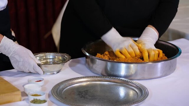 Close-up of gloved hands shaping kibbeh dough, forming traditional Middle Eastern stuffed bulgur balls, highlighting texture, technique, and hygienic food preparation process.