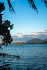 Fototapeta premium Sunset beach with boats at Bolilanga Island, Togian archipelago, Sulawesi, Indonesia