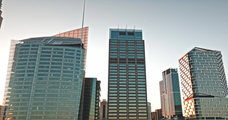Obraz premium Sydney skyscrapers in central business district reflecting warm sunset light, showcasing modern architecture and urban development against clear sky, symbolizing business and finance. Aerial panorama