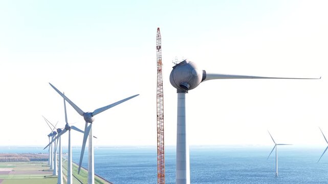 Wind turbine construction with a huge crane at a wind park in Flevoland Netherlands. Aerial view drone photo from above.