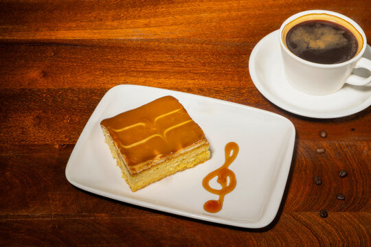 A slice of cake with a caramel glaze shaped like a coffee cup and a musical note on a white plate&mdash;the Turkish dessert Trili&ccedil;e.