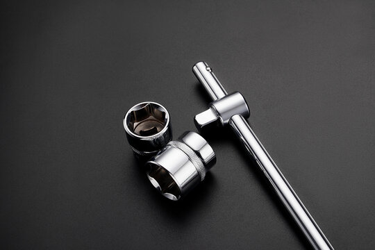 Professional chrome socket wrench set with T handle bar and hexagonal sockets on black background. High quality mechanical hand tools for automotive repair and maintenance.