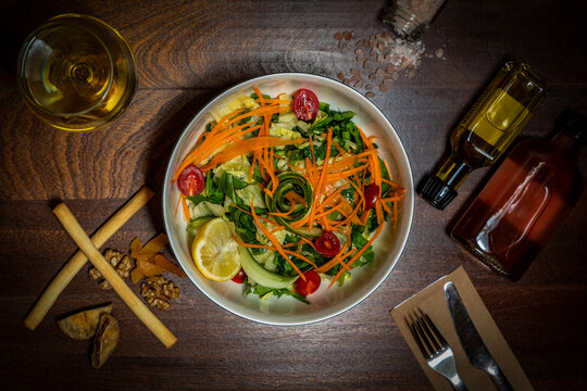 Fresh Healthy Vegetable Salad Bowl With Carrots, Cherry Tomatoes, Cucumber and Lemon on Wooden Table