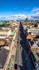 Obraz premium An elevated view showcases a long city street lined with buildings and bustling traffic, under a clear blue sky