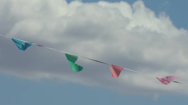 Bright party bunting flags blowing in wind under cloudy sky