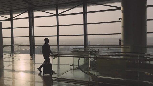 Silhouette Man Walking in Airport Terminal Toward Boarding Gate Travel Concept