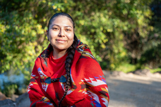 Peruvian woman wearing a traditional patterned poncho, smiling at the camera outdoors