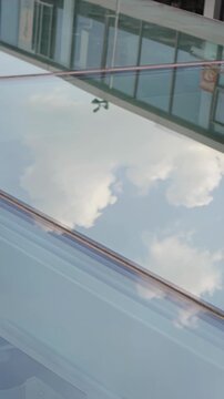Modern glass facade reflects drifting clouds and subtle city movement, creating a sleek urban visual with dynamic reflections, ideal for business presentations, architecture marketing