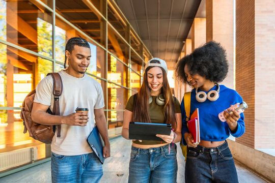 Diverse students walking on university campus discussing digital content