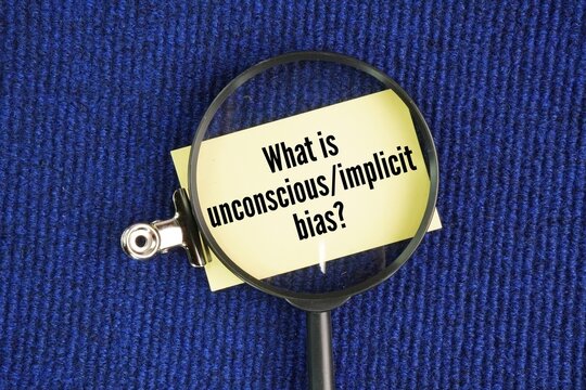 Magnifying glass and paper with the question words What is unconscious/implicit bias? Unconscious bias occurs when social stereotypes about certain groups affect judgment without the person realizing 