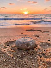 Fototapeta premium A serene beach scene at sunset with a single rock in focus.