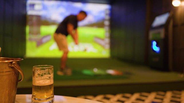 Man Playing Indoor Golf Simulator with Beer and Ice Bucket