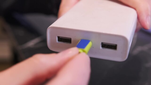 hand inserting micro usb cable close-up shot into power bank port, device charging process showing portable battery connection and energy supply setup in everyday mobile usage