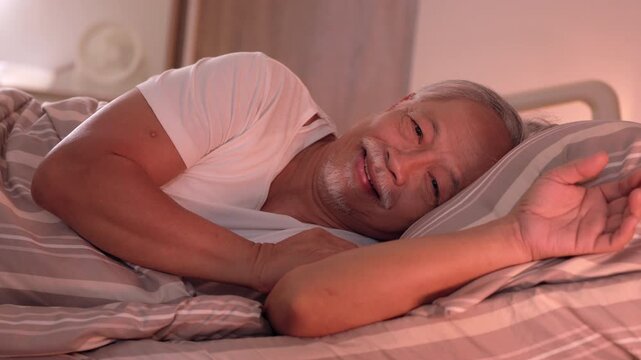 Happy senior man smiling on comfortable hospital bed with oxygen tube enjoying peaceful deep sleep after exhaustion and headache during medical patient recovery resting head upon soft pillow