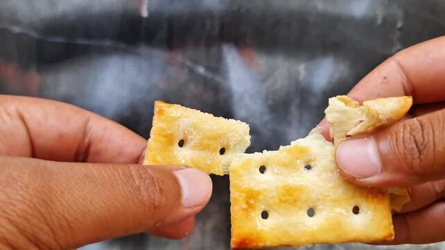 Sidoarjo, Indonedia - 30 April 2026: Crispy Golden Brown Sugar Crackers Held by Hand Delicious Crunchy Sweet and Salty Snack