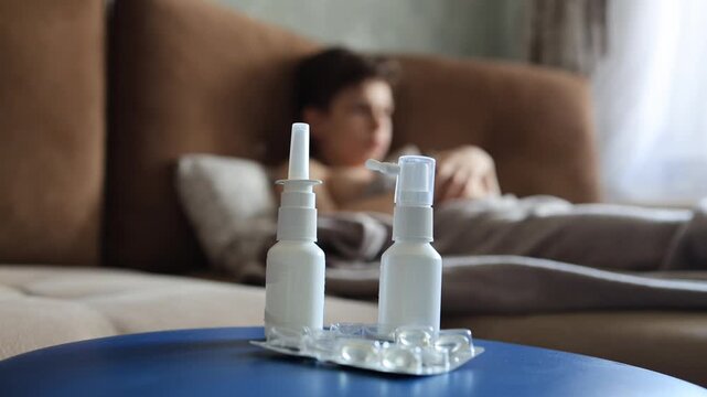 sick man lying in bed suffering virus having medicine tablets. drinking pill. A sick teenager lies on the couch, coughing and taking pills for a seasonal virus.