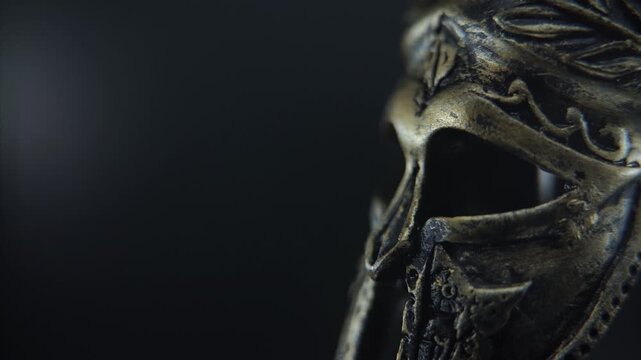 Dramatic close up of gladiator armor helmet rotating, illuminated by soft studio light and reflections